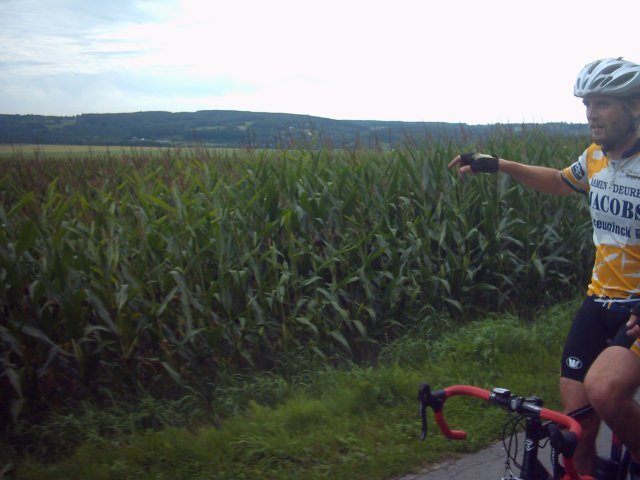 Wijds uitzicht 1
Voorbij HarzÃ© lag er tegen een beboste helling een echte Ardense vierkantshoeve waar de weg voorlangs passeerde en vanwaar je een mooi uitzicht had op de glooiende weiden, en de bergkammen aan de horizon. Raf in zijn gebruikelijke aanwijshouding als hij onderweg is. Op de volgende foto is het uitzicht beter gekadreerd.
