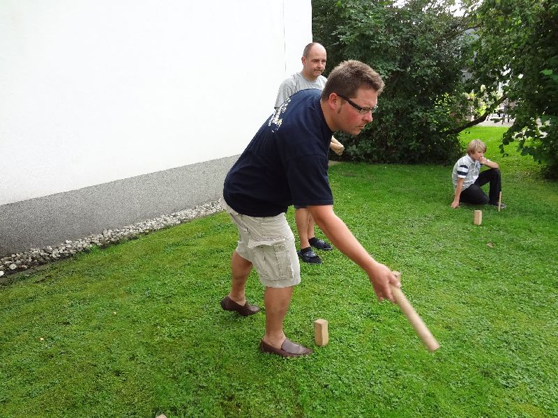 De voorzitter steekt een stokje bij terwijl de buurjongen toekijkt. Wat later speelt hij mee.
